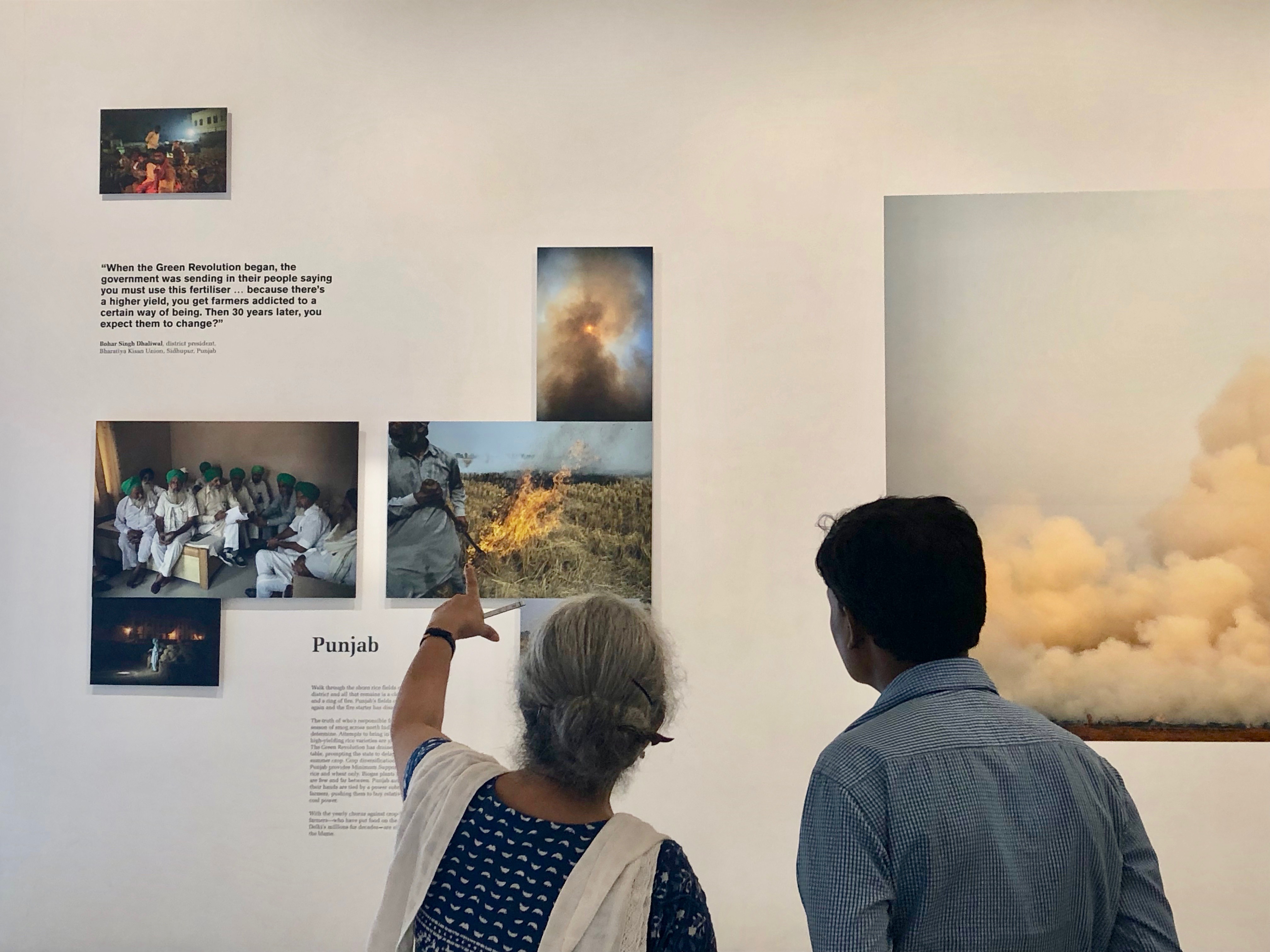 Two people looking at a photo exhibit of pollution