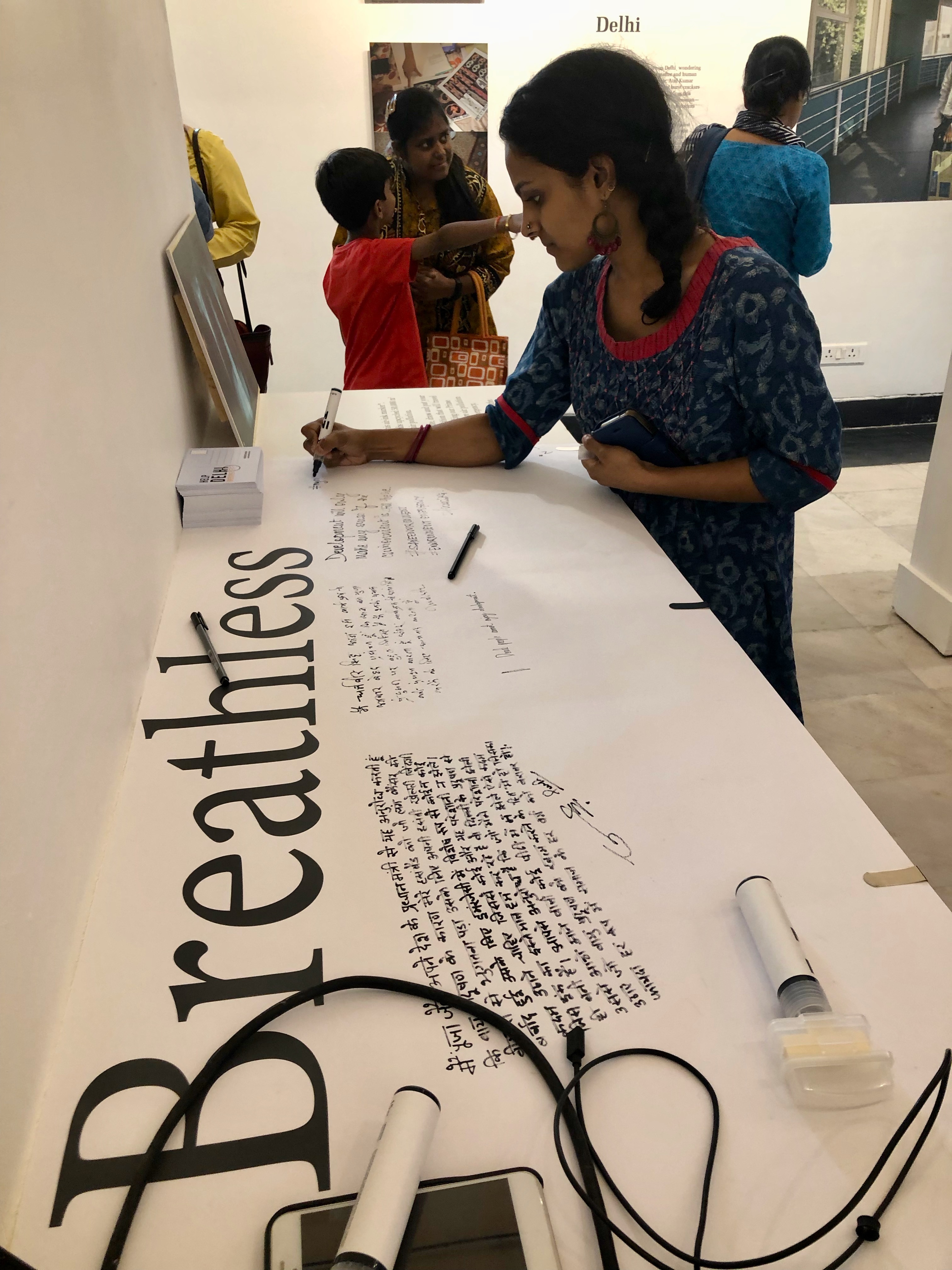 A woman writing on a poster that says "Breathless"