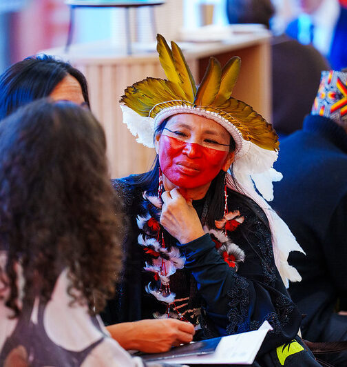 A woman in indigenous dress listens to fellow Davos attendees speak.